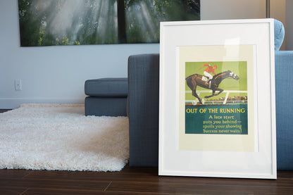 Out of the Running poster in a white frame leaning beside a blue sofa