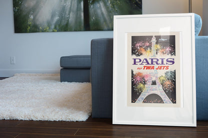 Paris Fly TWA Jets Fireworks poster leaning beside a blue sofa