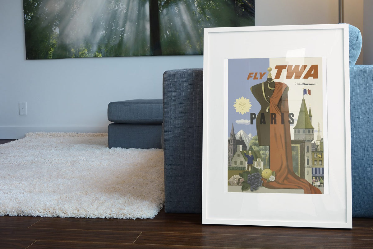 Paris Fly TWA 1950s poster leaning beside a blue sofa