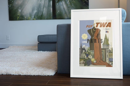 Paris Fly TWA 1950s poster leaning beside a blue sofa