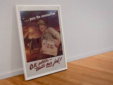 Pass the Ammunition OK Soldier Thats Our Job poster in a white frame leaning against a wall
