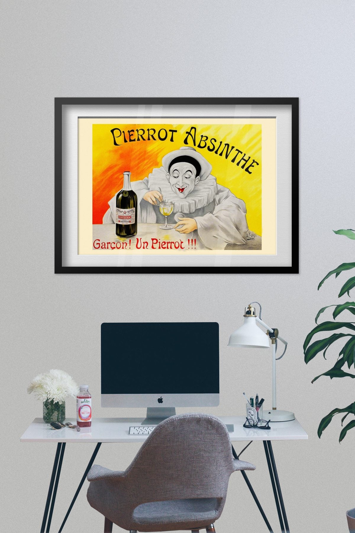 Pierrot Absinthe poster framed on a grey wall above a desk