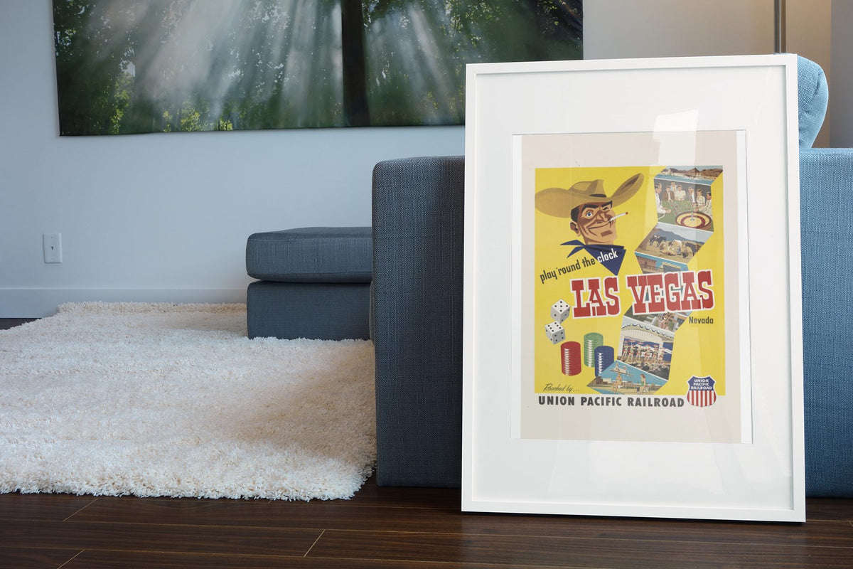 Play Round the Clock Las Vegas poster leaning beside a blue sofa