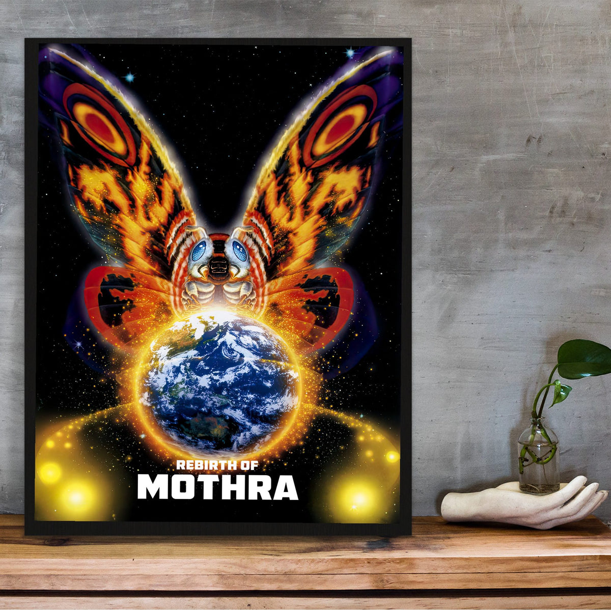 Rebirth of Mothra (1996) Movie Key Art poster in a black frame on a wooden shelf against concrete