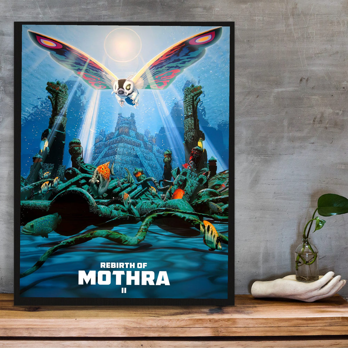 Rebirth of Mothra II (1997) Movie Key Art poster in a black frame on a wooden shelf against concrete