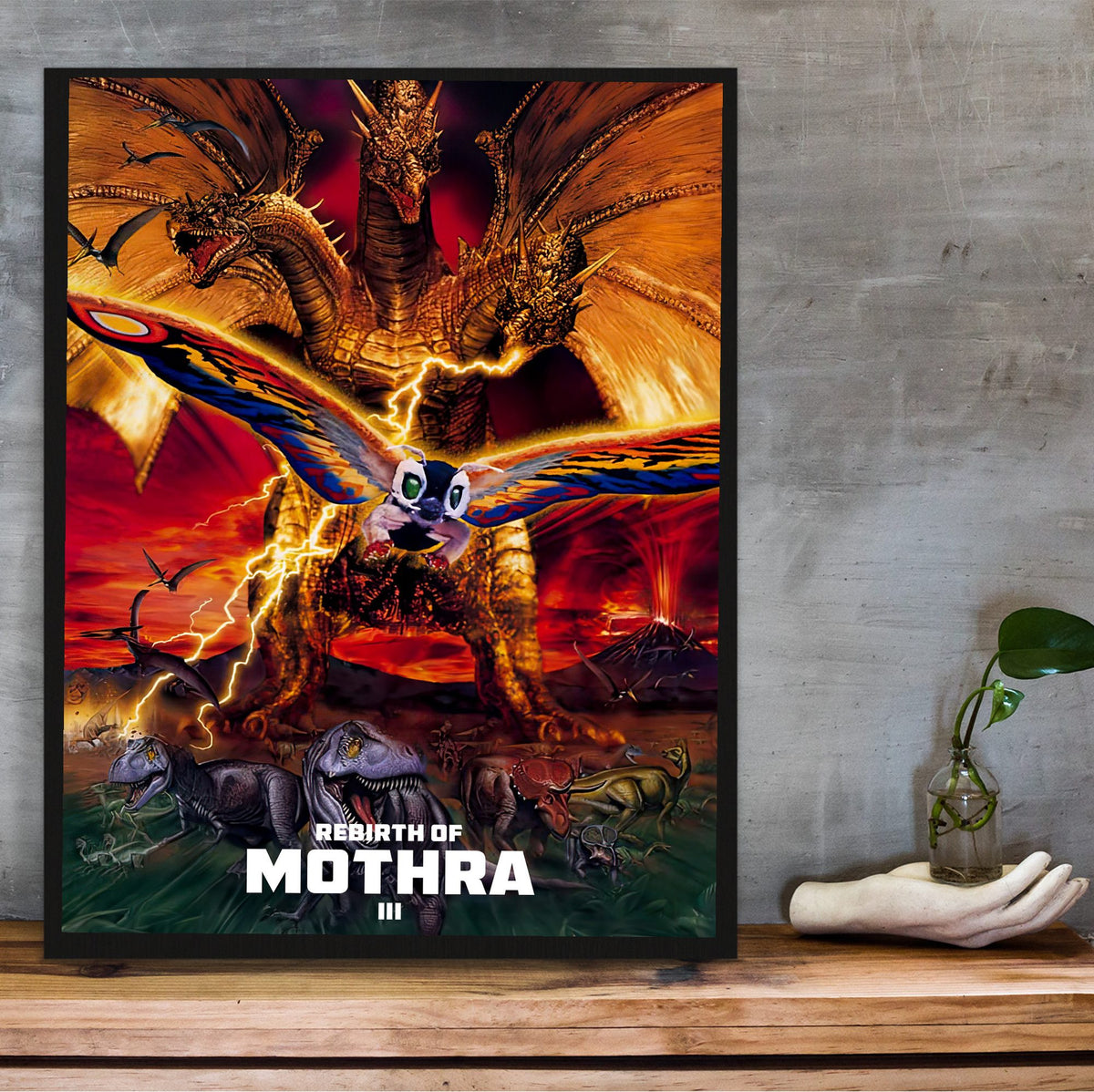Rebirth of Mothra III (1998) Movie Key Art poster in a black frame on a wooden shelf against concrete