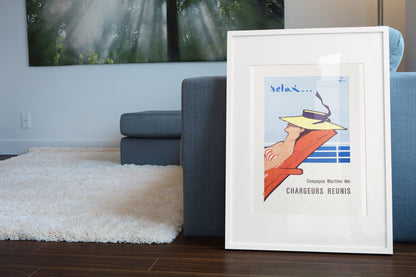Relax Chargeurs Reunis poster leaning beside a blue sofa