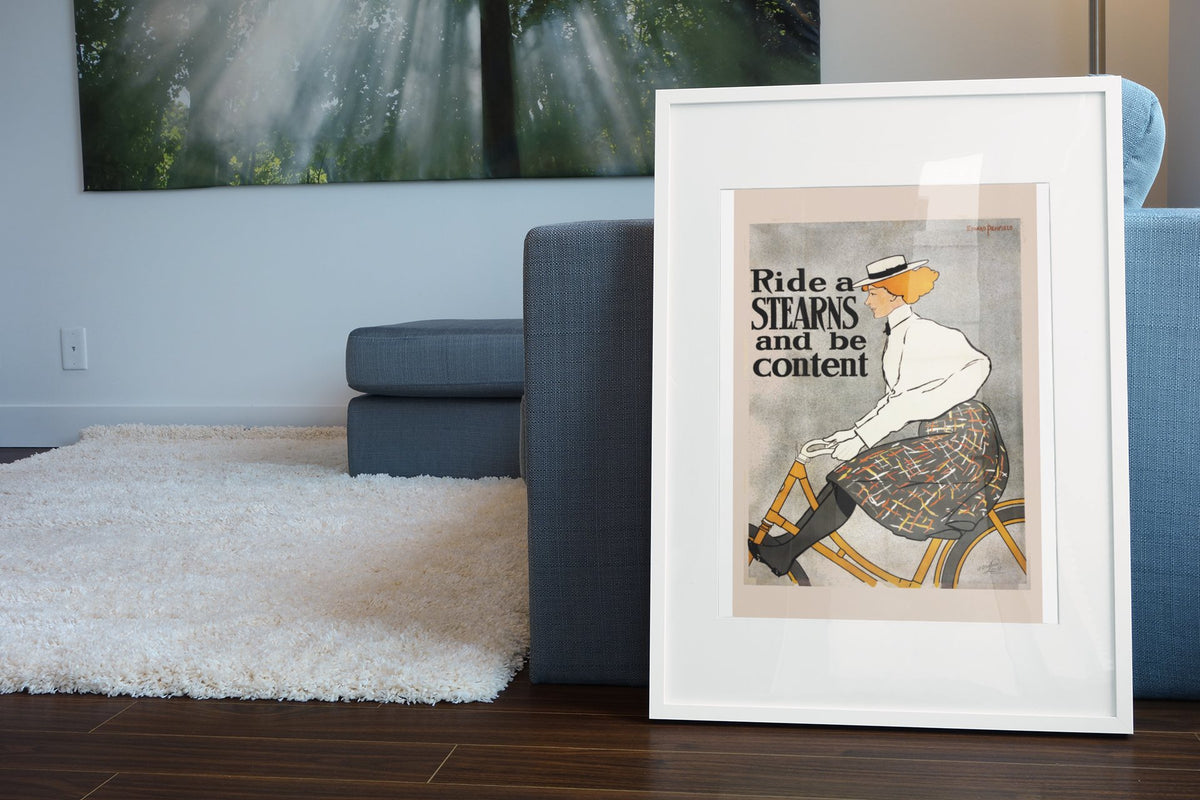 Ride a Stearns and Be Content poster leaning beside a blue sofa