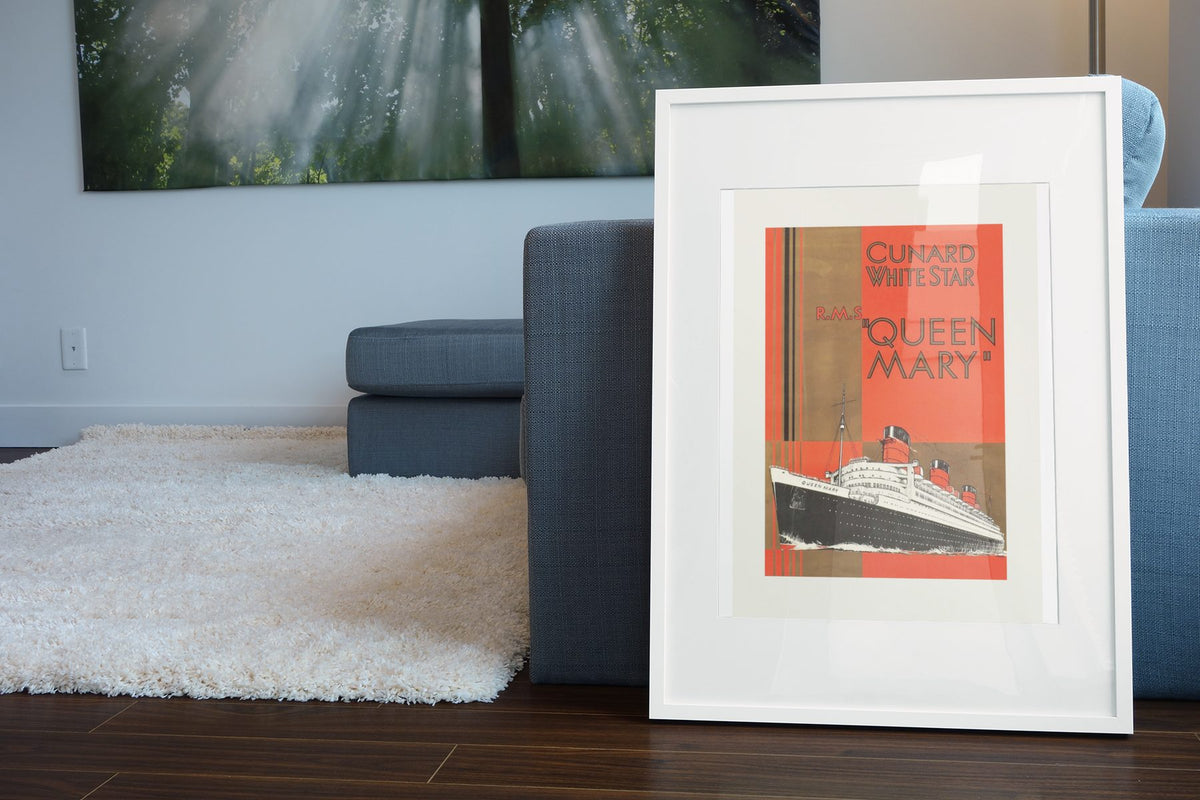 RMS Queen Mary Cunard White Star poster leaning beside a blue sofa