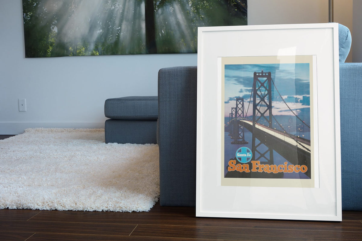 San Francisco Bay Bridge Santa Fe poster leaning beside a blue sofa