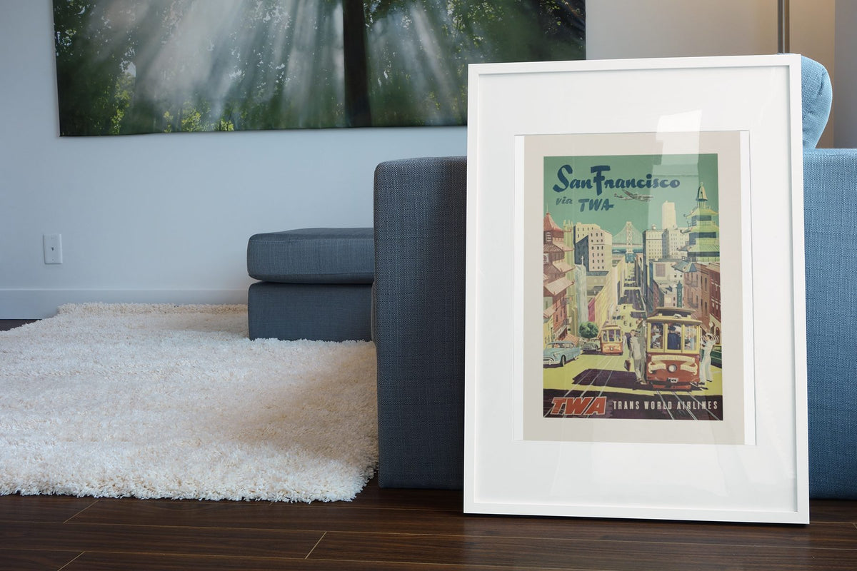San Francisco Fly TWA Cable Car poster leaning beside a blue sofa