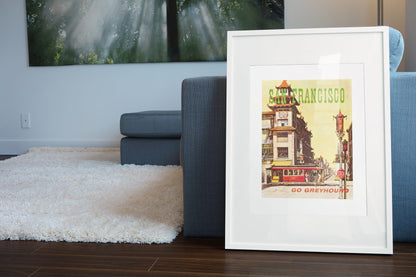 San Francisco Go Greyhound poster leaning beside a blue sofa