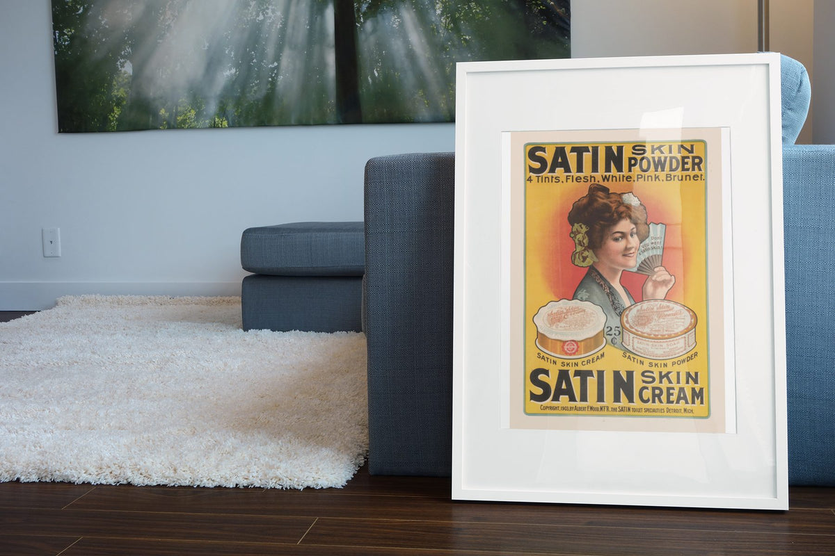 Satin Skin Powder poster leaning beside a blue sofa