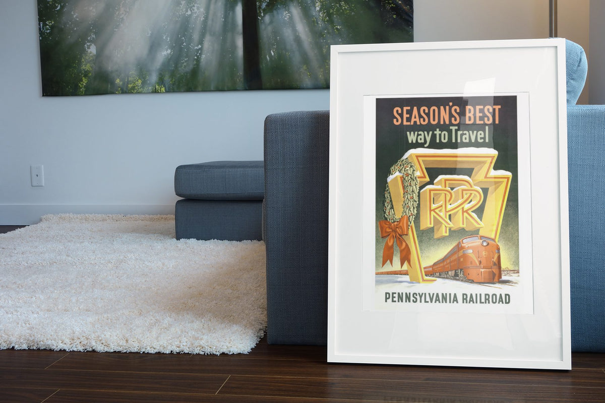 Seasons Best Way to Travel PRR poster leaning beside a blue sofa