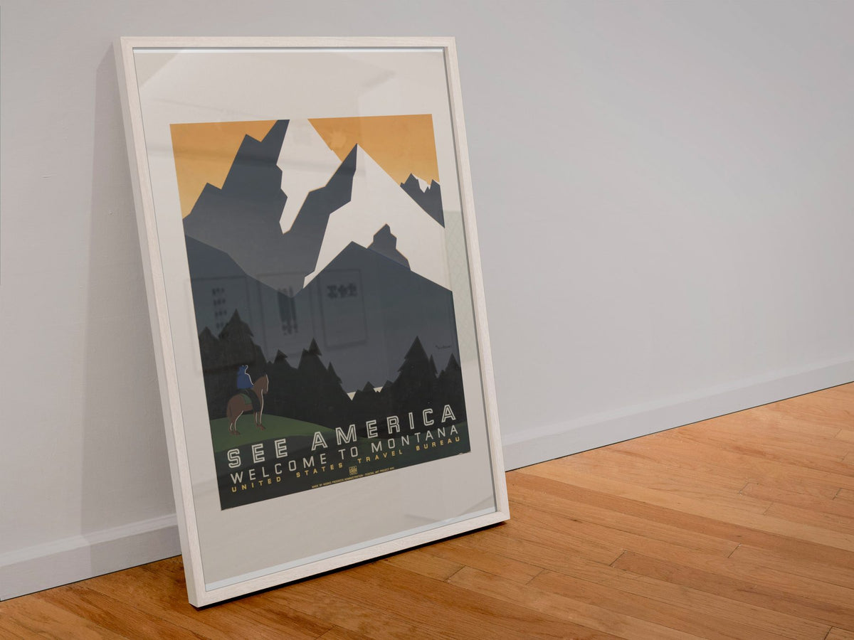 See America Welcome to Montana poster in a white frame leaning against a wall