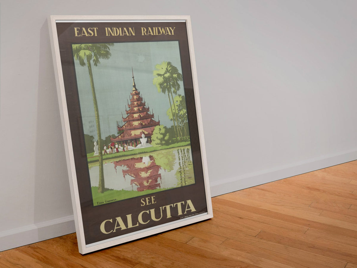 See Calcutta — East Indian Railway poster in a white frame leaning against a wall