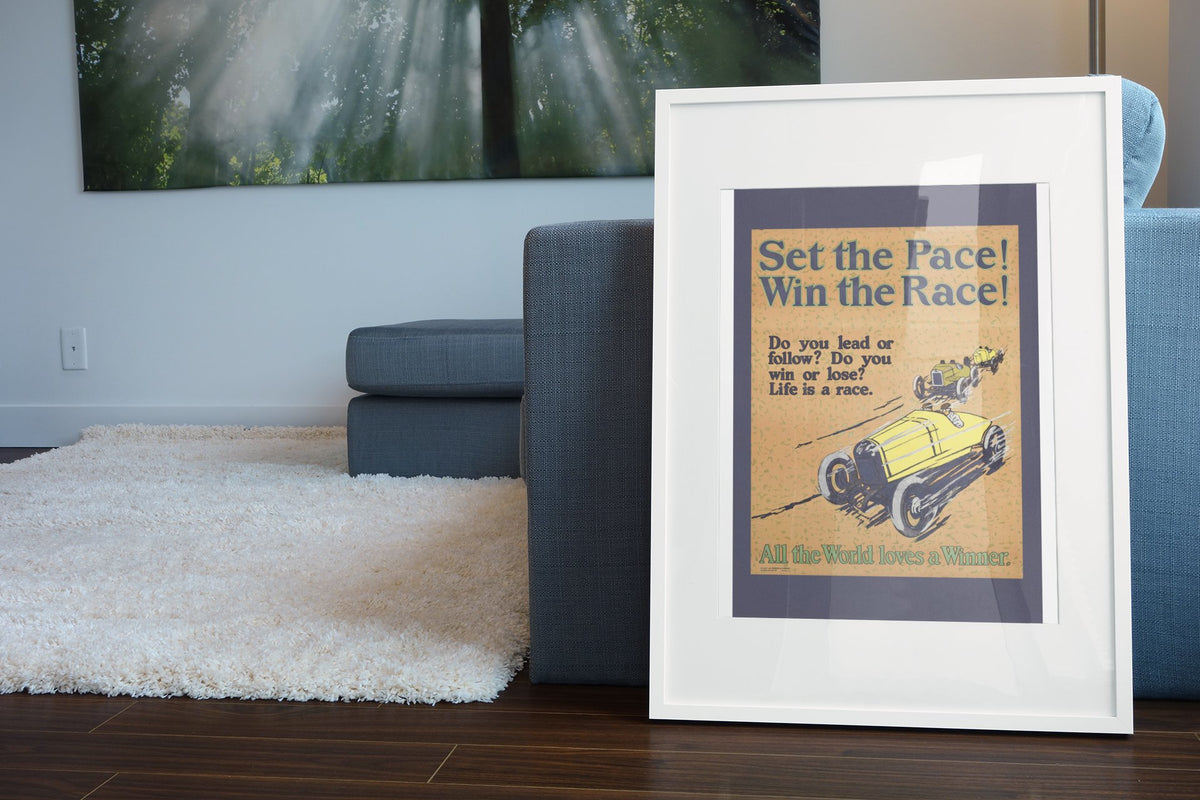 Set the Pace! Win the Race! poster in a white frame leaning beside a blue sofa