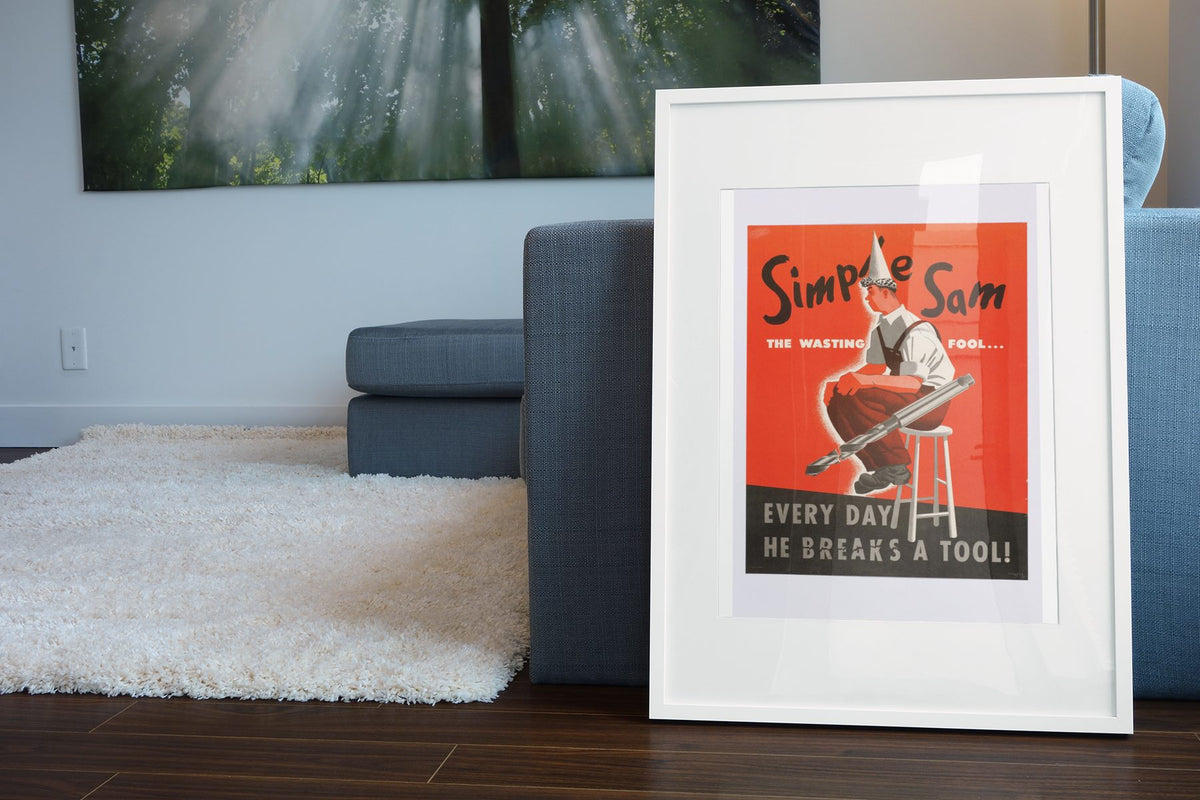 Simple Sam the Wasting Fool poster leaning beside a blue sofa