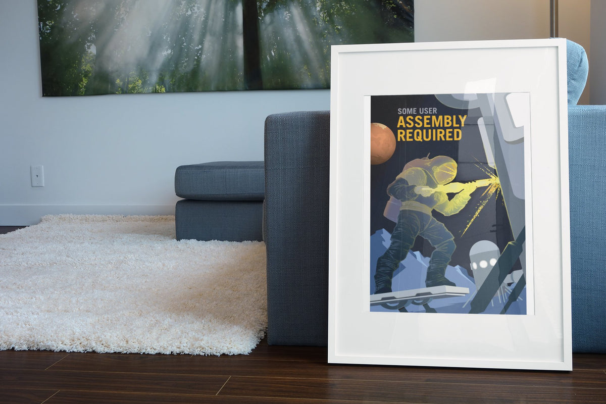 Some User Assembly Required poster in a white frame leaning beside a blue sofa