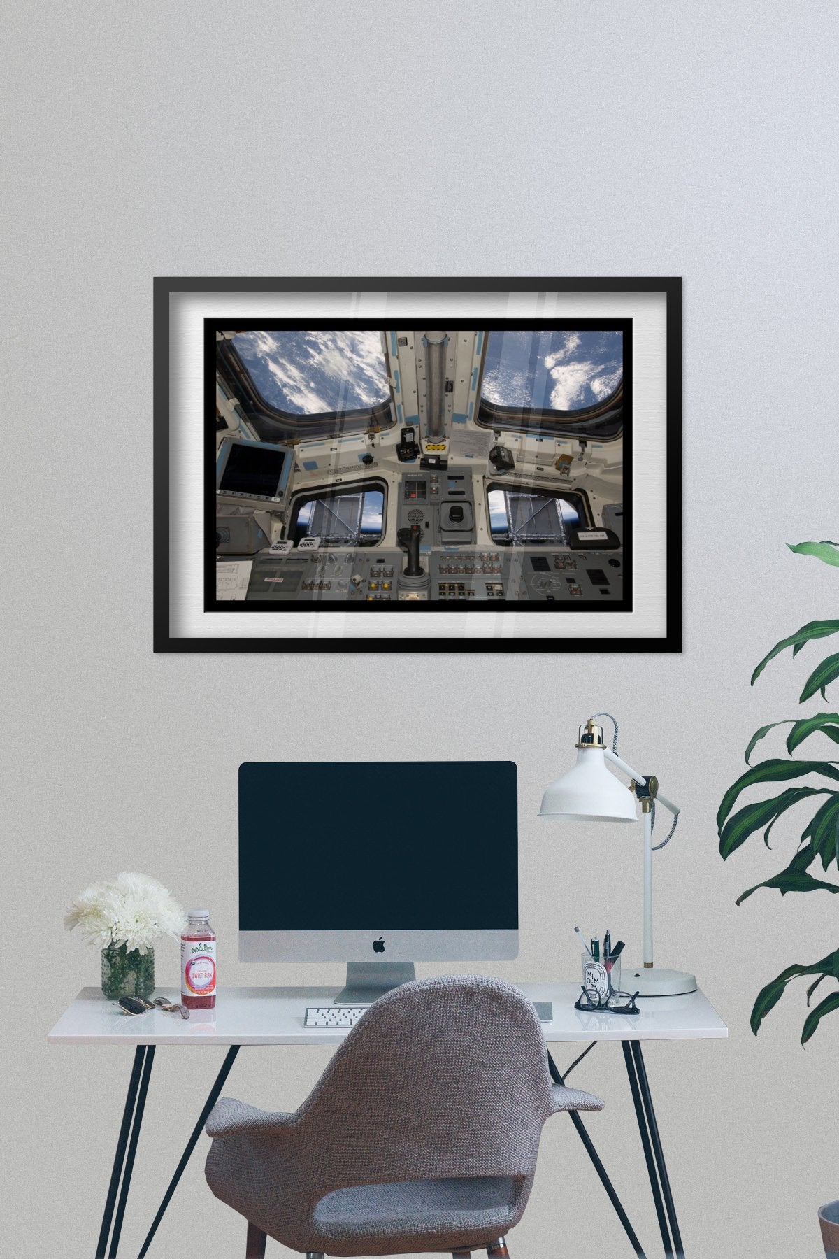 Space Shuttle Atlantis cockpit poster framed above a desk with a computer