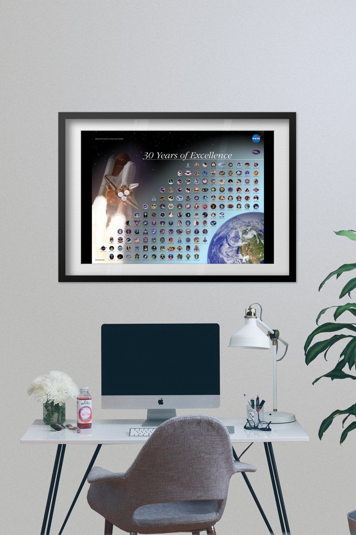 Space Shuttle mission patches, 30 Years of Excellence poster framed above a desk with a computer