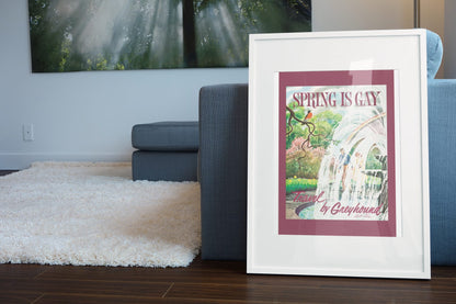 Spring is Gay Greyhound poster leaning beside a blue sofa