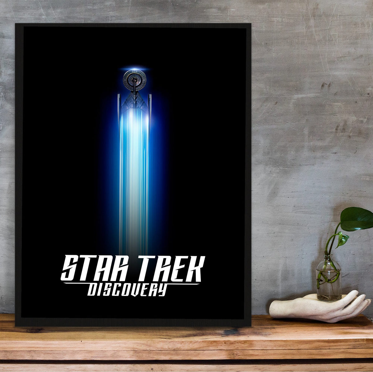 Star Trek: Discovery poster in a black frame on a wooden shelf against concrete