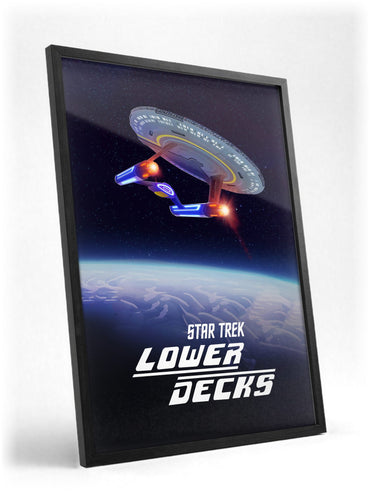 Star Trek: Lower Decks poster in a black frame with glass leaning against a wall
