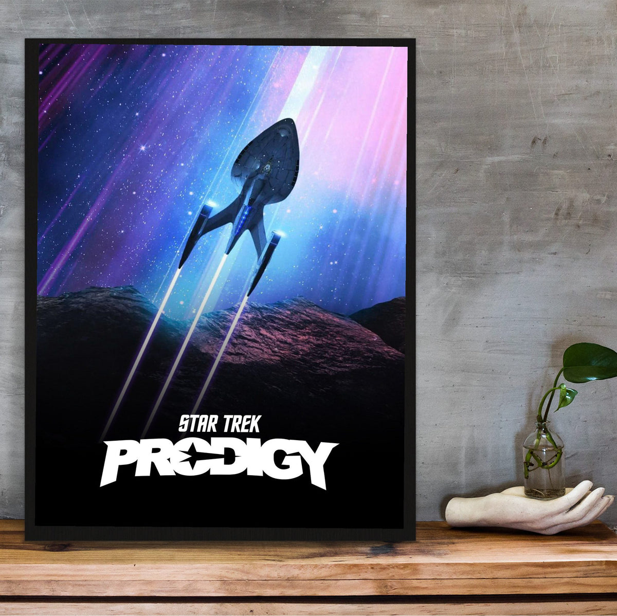 Star Trek: Prodigy poster in a black frame on a wooden shelf against concrete