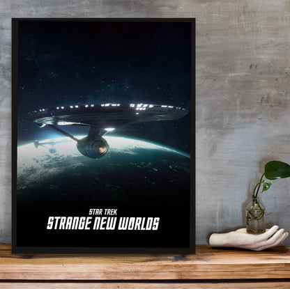 Star Trek: Strange New Worlds poster in a black frame on a wooden shelf against concrete