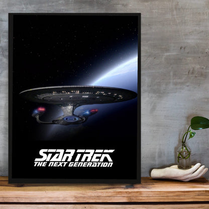 Star Trek: The Next Generation poster in a black frame on a wooden shelf against concrete