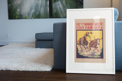 State Fair Rodeo Steer Wrestler poster leaning beside a blue sofa