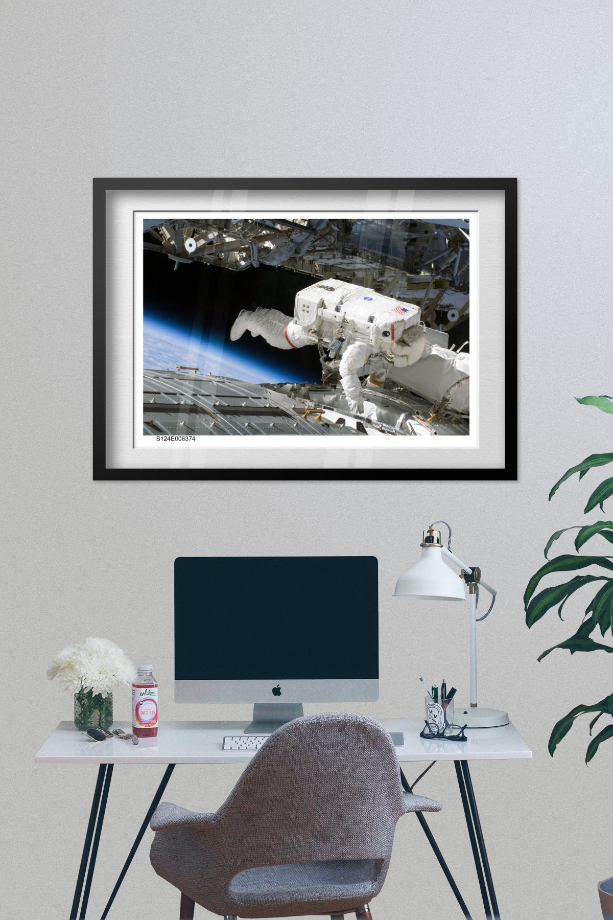 STS-124 Discovery astronaut spacewalk poster framed above a desk with a computer