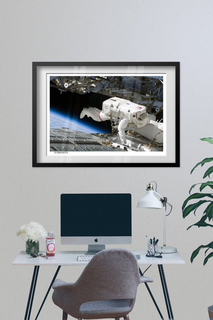 STS-124 Discovery astronaut spacewalk poster framed above a desk with a computer