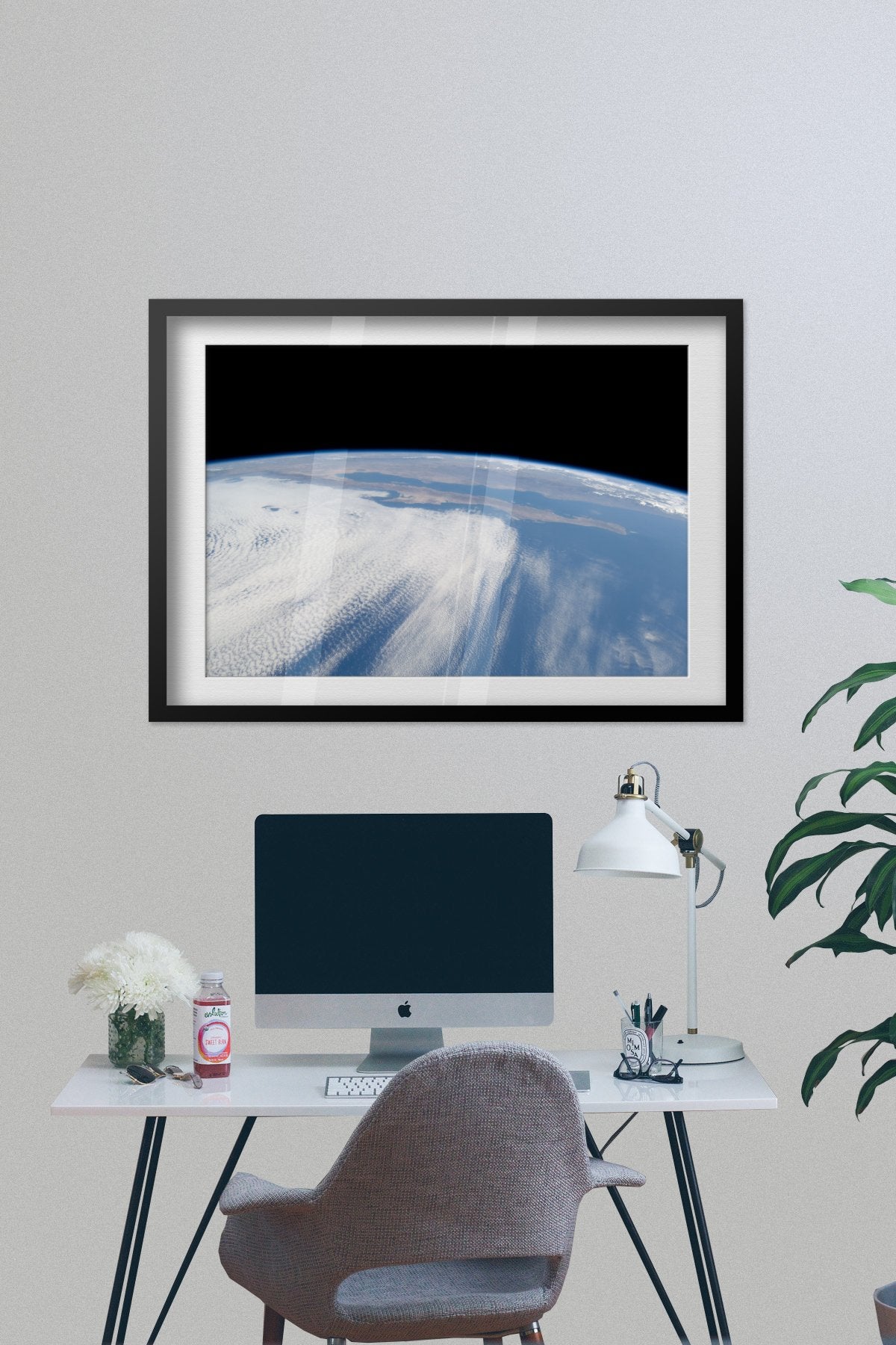 STS-125 view of Earth from Space Shuttle Atlantis poster framed above a desk with a computer