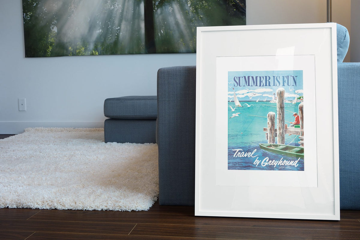Summer is Fun Greyhound poster leaning beside a blue sofa