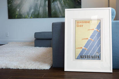 Sunshine and Surf Australia poster leaning beside a blue sofa