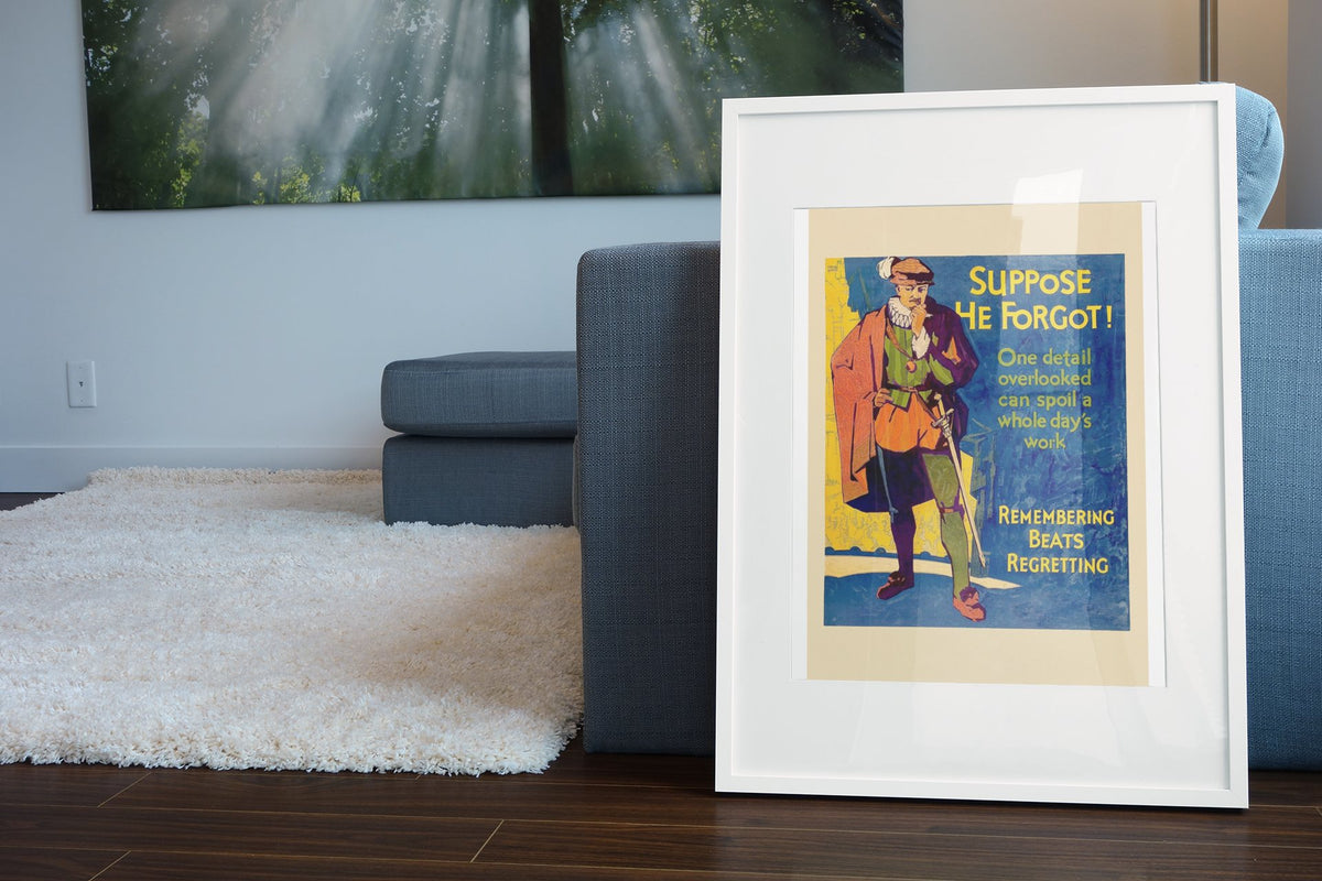 Suppose He Forgot poster in a white frame leaning beside a blue sofa