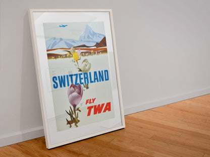 Switzerland Fly TWA poster in a white frame leaning against a wall