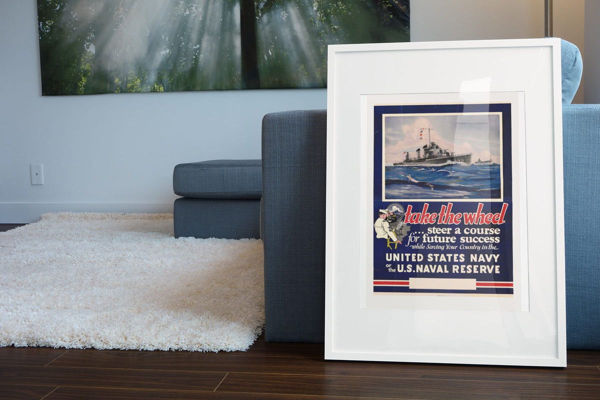 Take the Wheel — U.S. Naval Reserve poster leaning beside a blue sofa