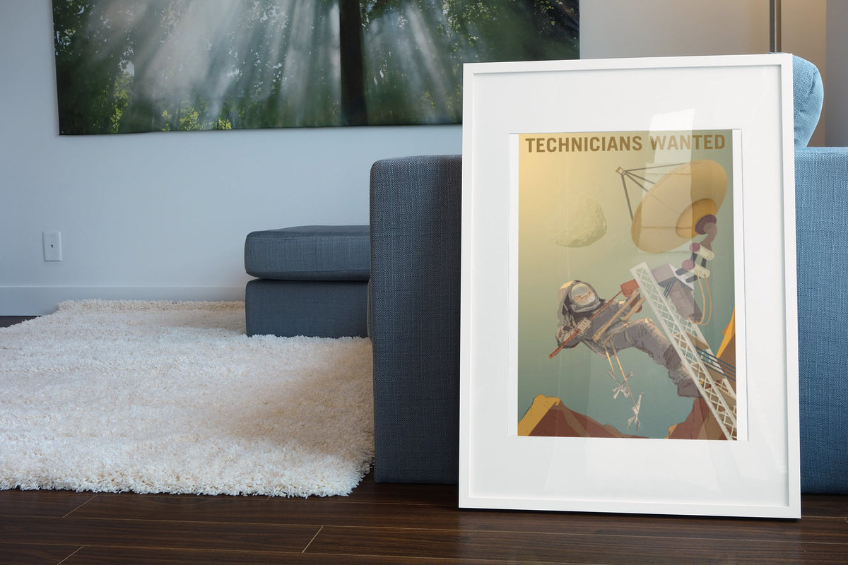 Technicians Wanted poster in a white frame leaning beside a blue sofa