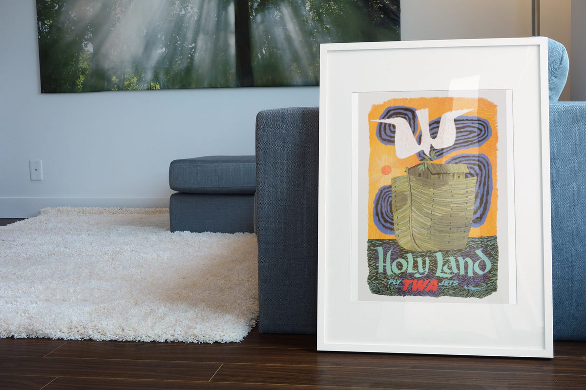 Holy Land Fly TWA poster leaning beside a blue sofa