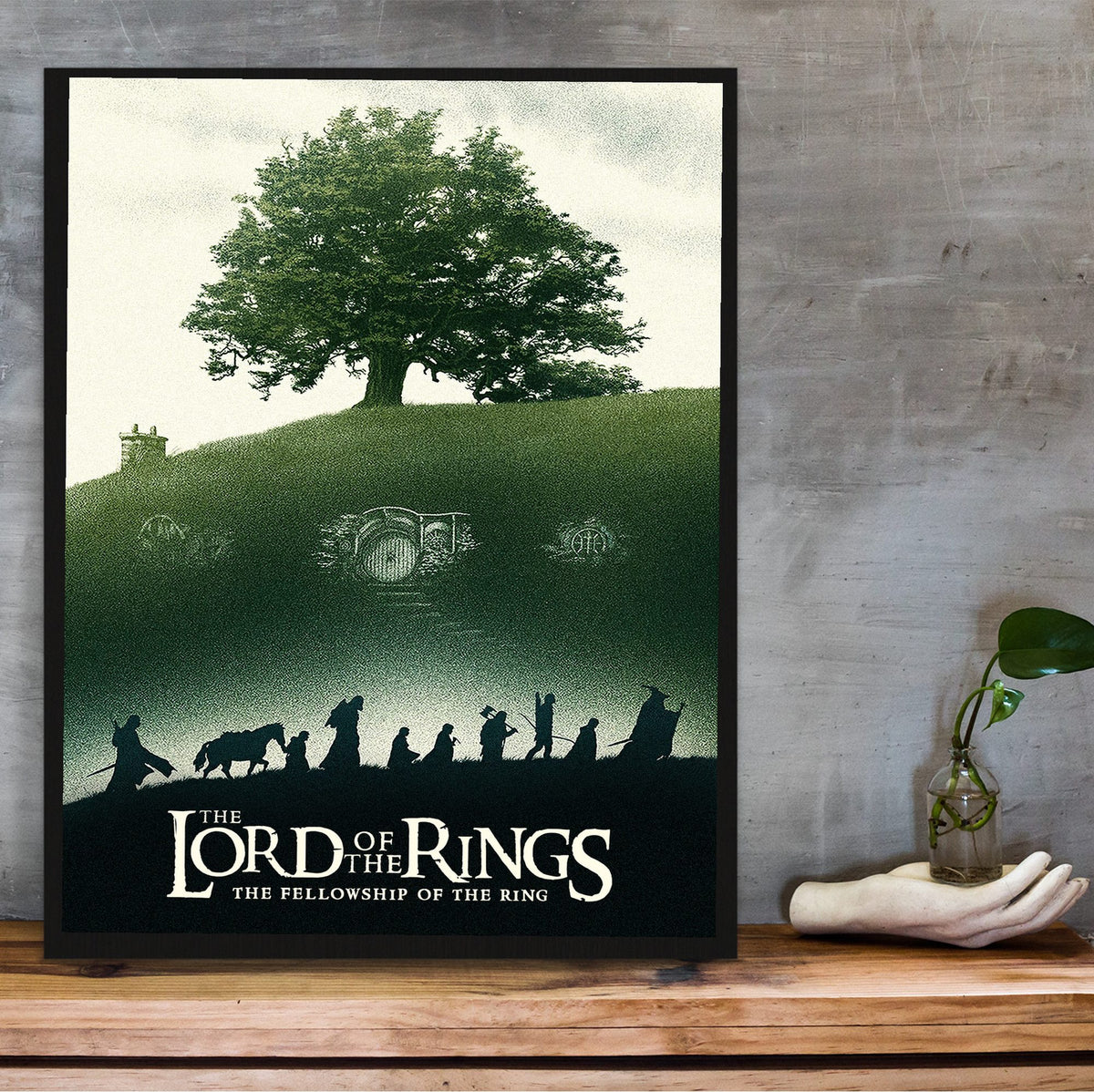 The Lord of the Rings: The Fellowship of the Ring (2001) Shire Tree Art poster in a black frame on a wooden shelf against concrete