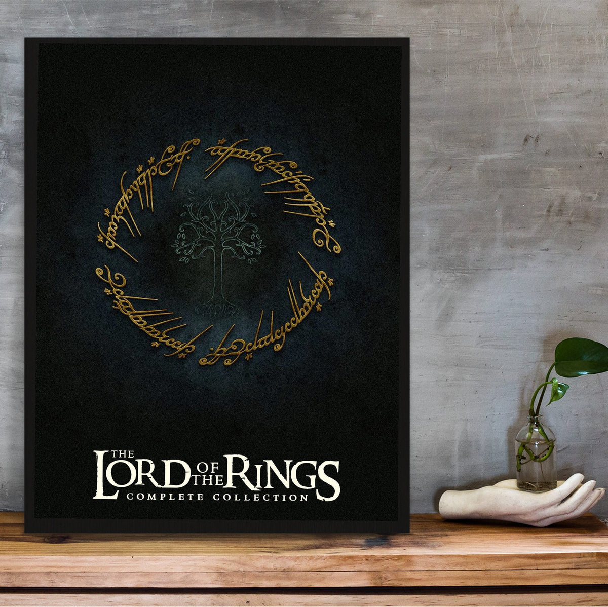 The Lord of the Rings Trilogy Movie One Ring Art poster in a black frame on a wooden shelf against concrete