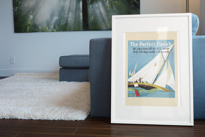 The Perfect Finish poster in a white frame leaning beside a blue sofa
