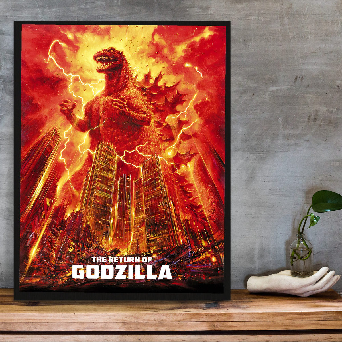 The Return of Godzilla (1984) Movie Illustrated Art poster in a black frame on a wooden shelf against concrete