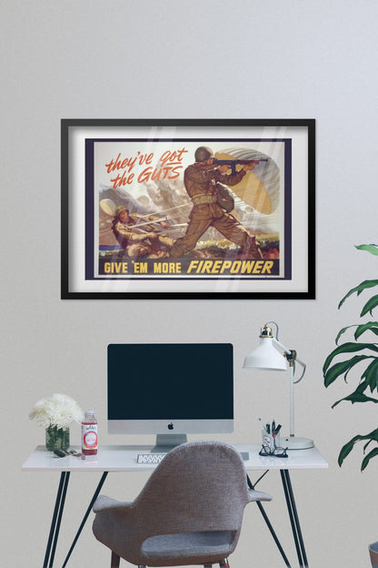 Theyve Got the Guts Give Em More Firepower poster framed on a grey wall above a desk