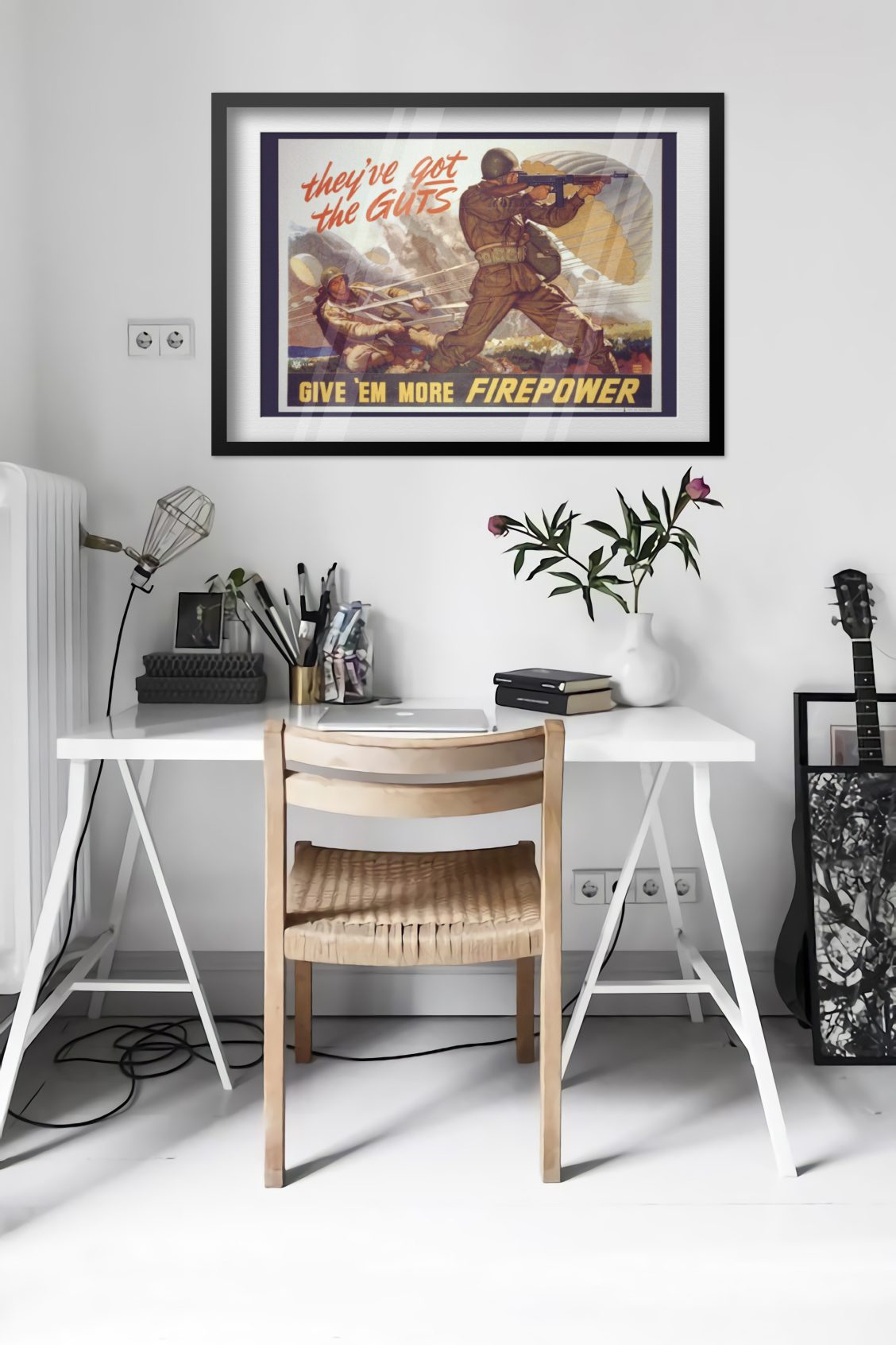 Theyve Got the Guts Give Em More Firepower poster framed above a desk in a bright white room