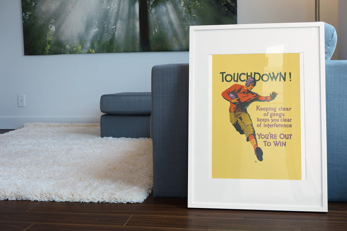 Touchdown poster in a white frame leaning beside a blue sofa