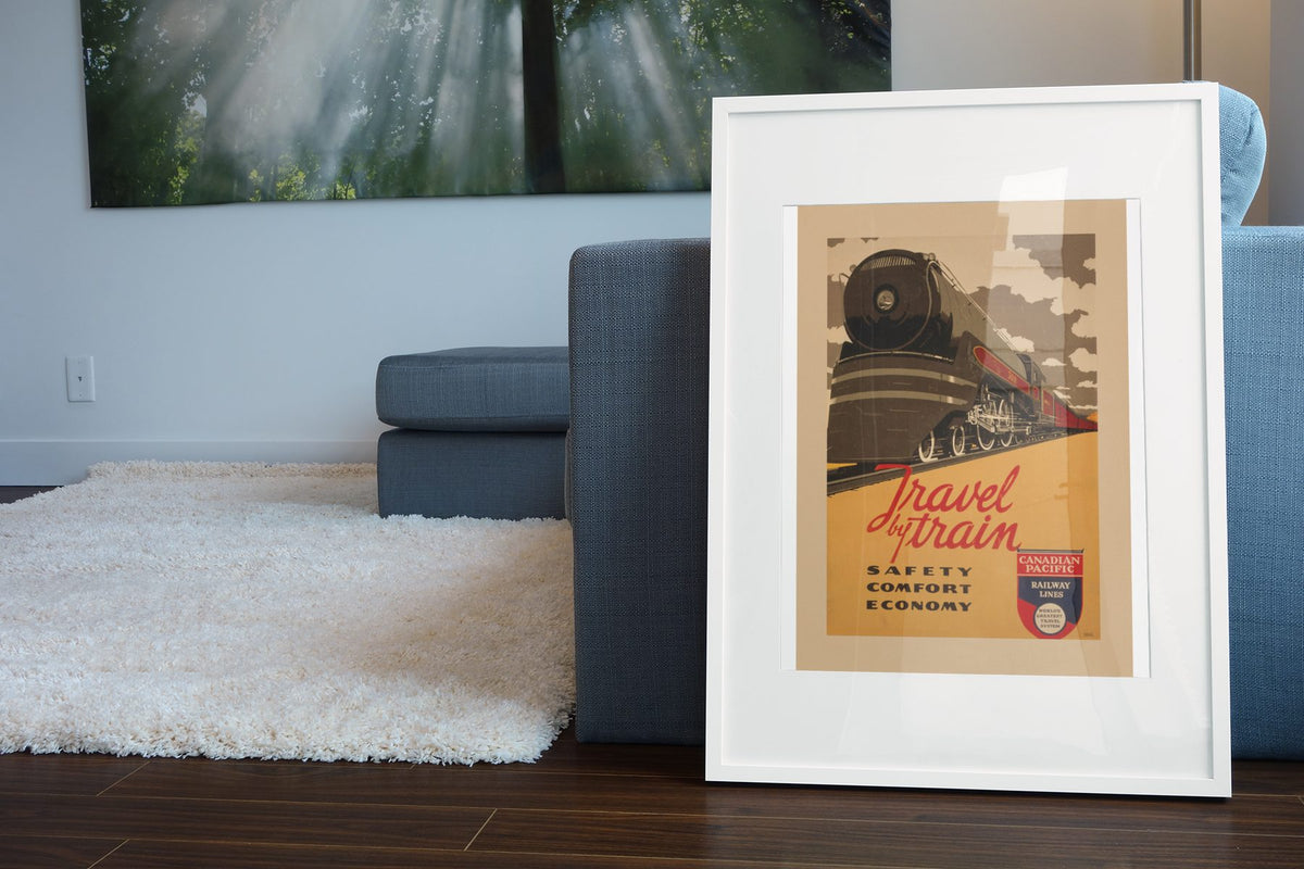 Travel by Train Canadian Pacific poster leaning beside a blue sofa